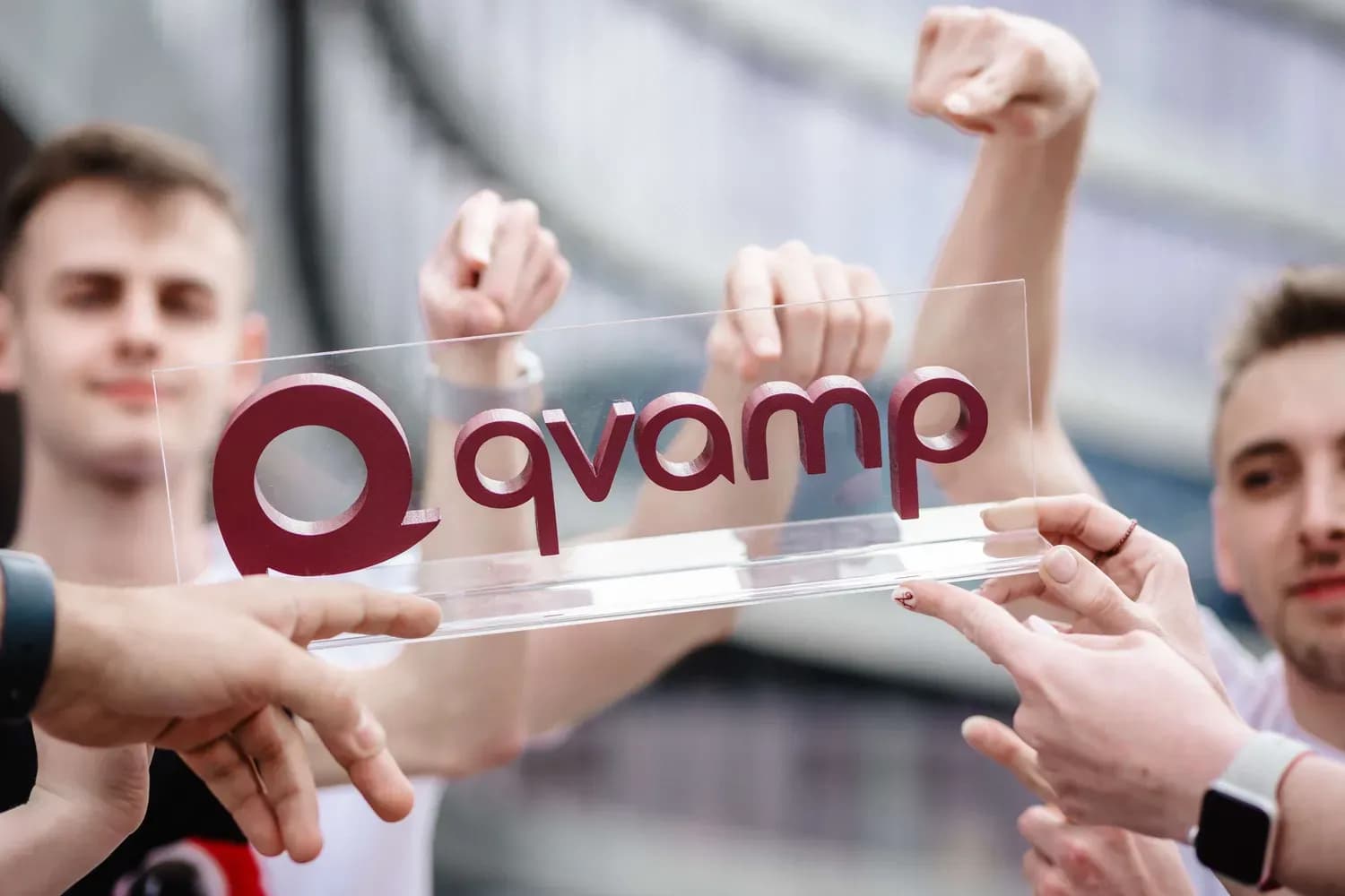 Dłonie zespołu Qvampu trzymają logo Qvamp